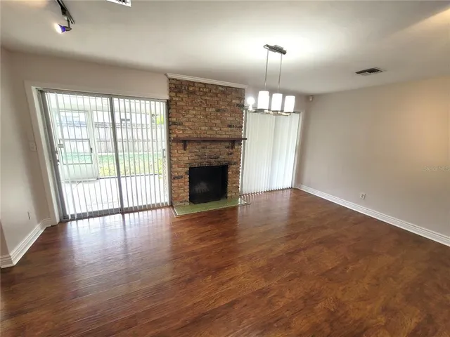 an empty room with wooden floor fireplace and windows