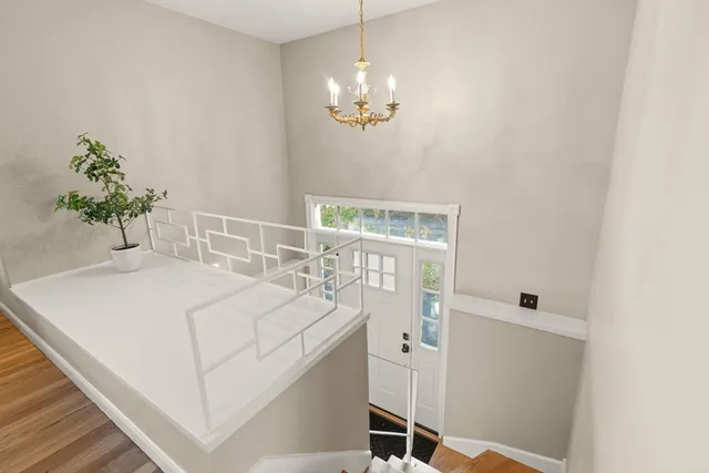 a room with a chandelier fan and wooden floor