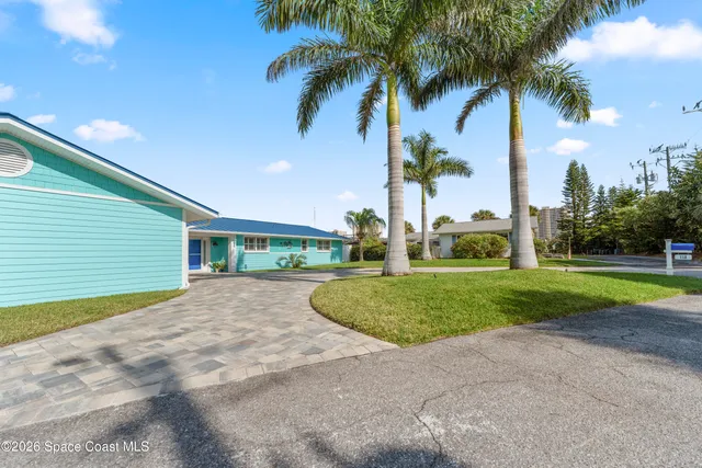 a view of a house with a yard and palm trees