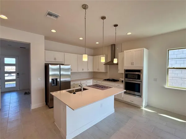 a kitchen that has a lot of cabinets and stainless steel appliances