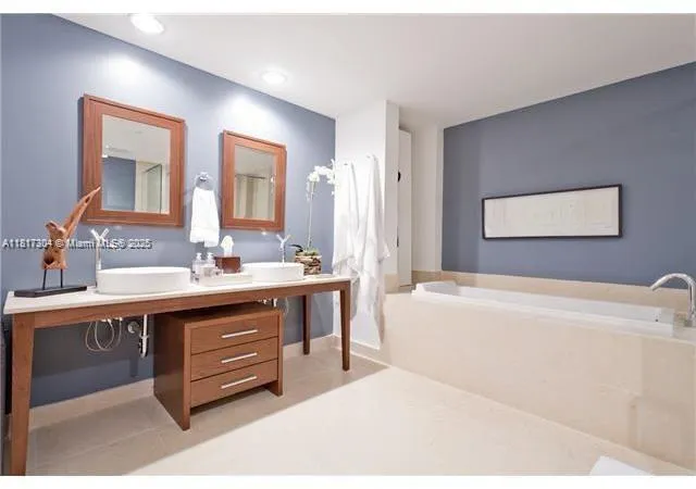 a spacious bathroom with a tub sink and mirror