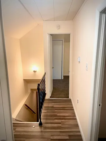 a view of a hallway with wooden floor and stairs