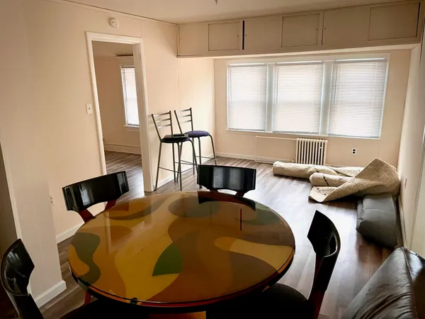 a view of an empty room with wooden floor and a window