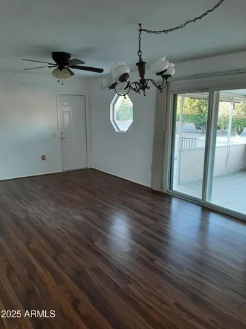 an empty room with wooden floor fan and windows