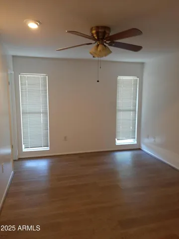an empty room with wooden floor closet and windows
