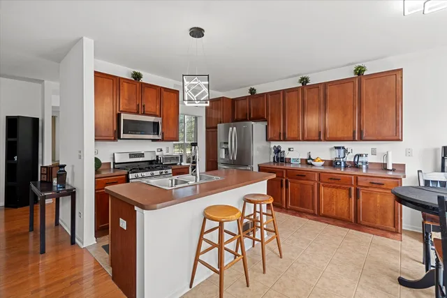 a kitchen with stainless steel appliances granite countertop a stove top oven a sink dishwasher a dining table and chairs with wooden floor