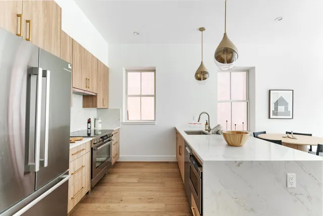 a kitchen with a refrigerator a sink dishwasher a kitchen island with wooden floor and cabinets