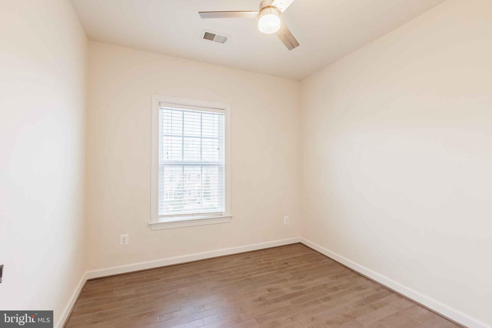 9733 Braidwood Terrace Frederick, MD 21704 - Photo 21 of 33 an empty room with wooden floor chandelier fan and windows