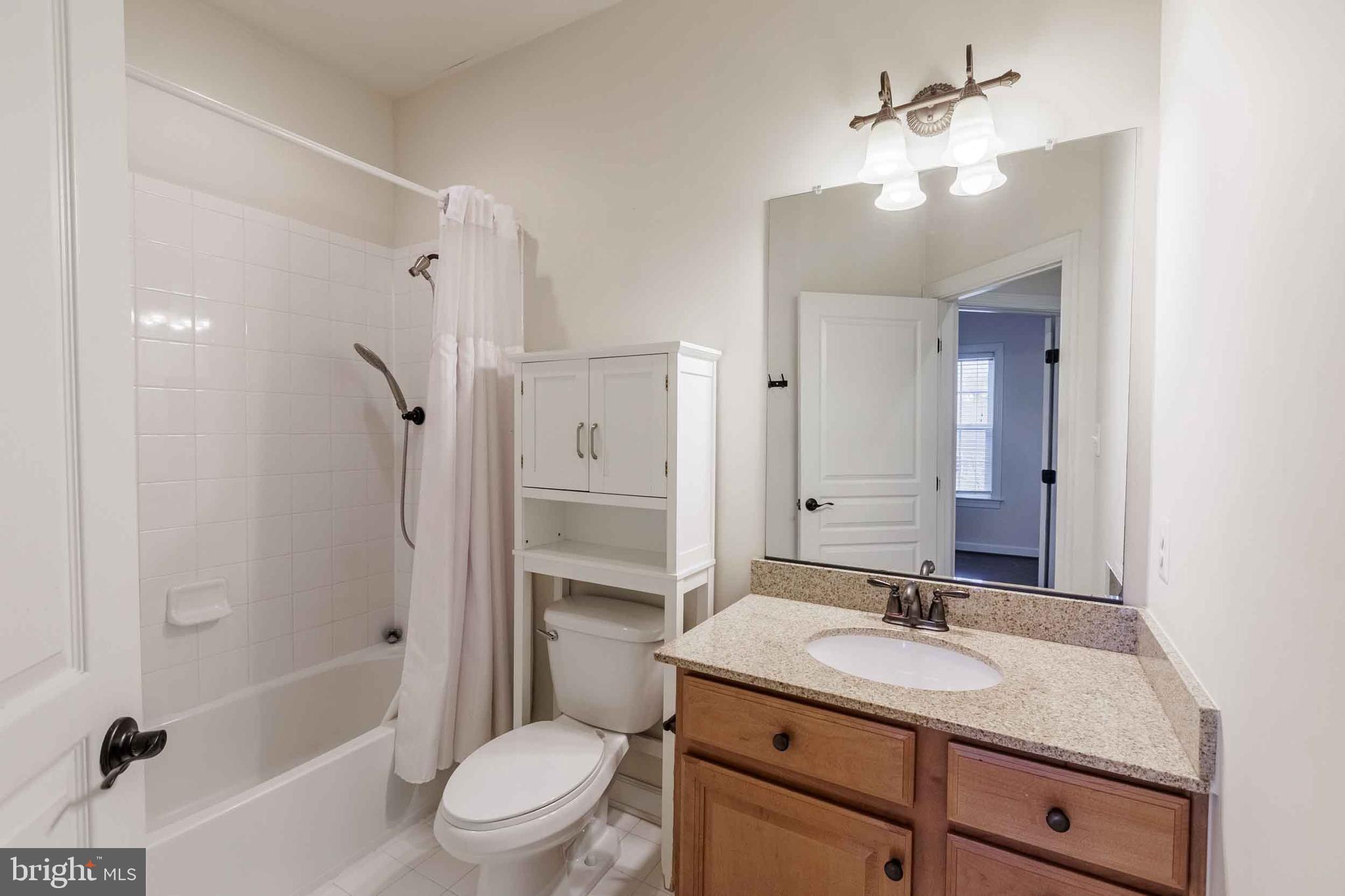 9733 Braidwood Terrace Frederick, MD 21704 - Photo 23 of 33 a bathroom with a granite countertop sink toilet a mirror and shower