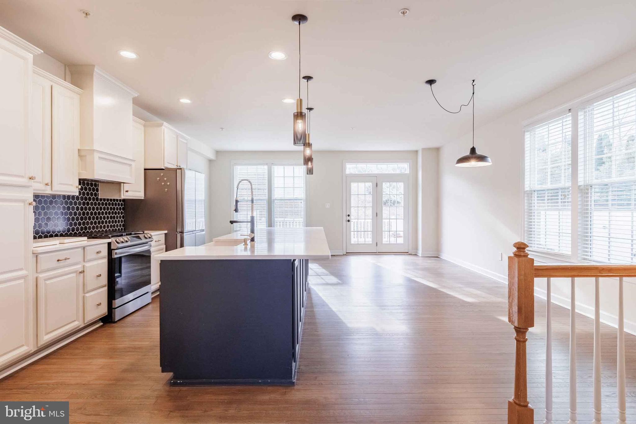 9733 Braidwood Terrace Frederick, MD 21704 - Photo 6 of 33 a large kitchen with stainless steel appliances kitchen island granite countertop a stove a sink dishwasher and a refrigerator with wooden floor