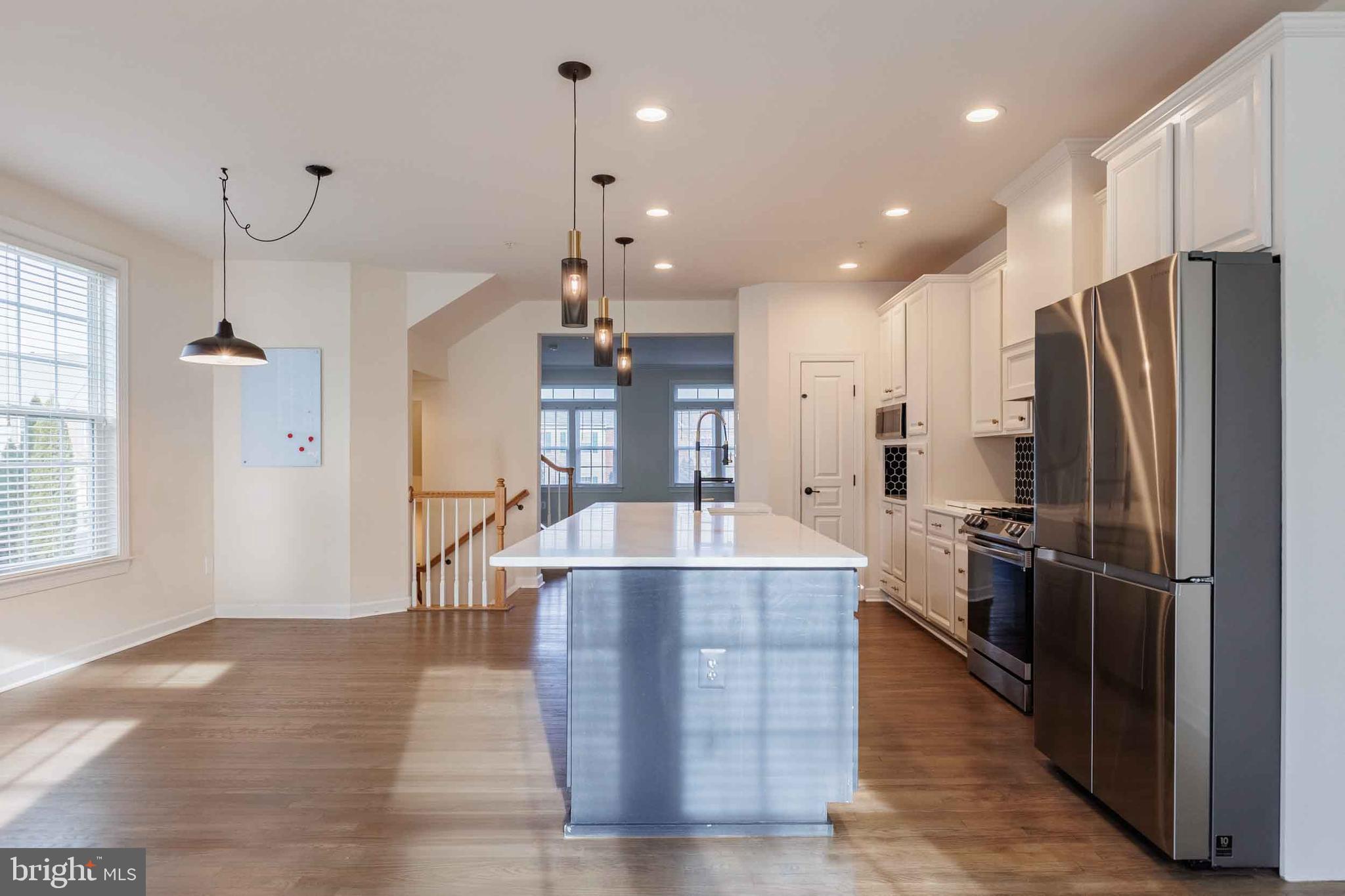 9733 Braidwood Terrace Frederick, MD 21704 - Photo 9 of 33 a large kitchen with stainless steel appliances kitchen island granite countertop a stove a refrigerator a sink and a oven with wooden floor