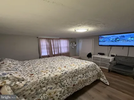 a bedroom with a bed and a dresser with wooden floor