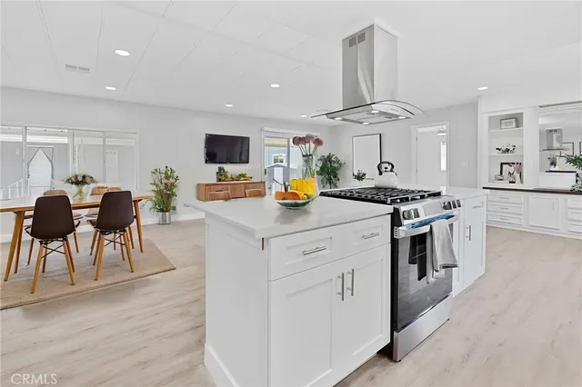 a kitchen with stainless steel appliances granite countertop a stove top oven a sink a dining table and chairs with wooden floor