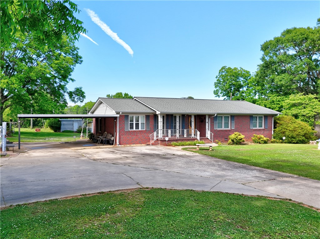 307 Calhoun Road Belton, SC 29627 - Photo 7 of 30 Brick ranch-style home with a covered carport and a generously proportioned front yard.