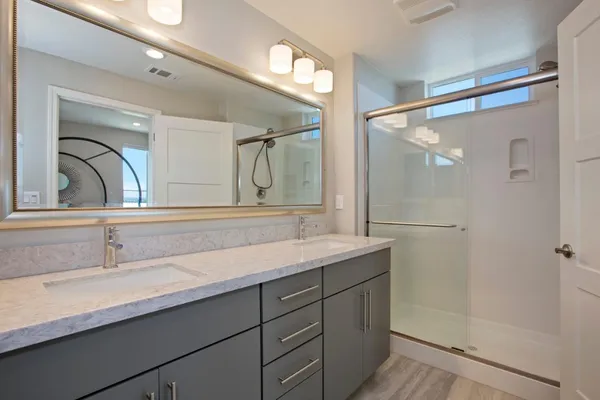 a bathroom with a granite countertop sink a mirror and shower