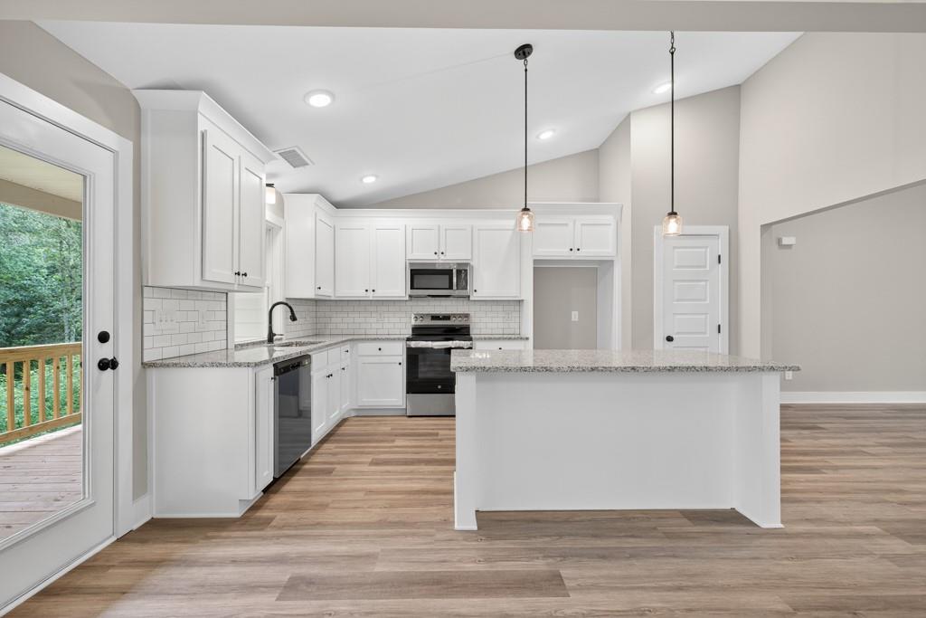 328 Advent Drive Winder, GA 30680 - Photo 11 of 45 a large kitchen with stainless steel appliances kitchen island granite countertop a stove a sink a refrigerator and white cabinets with wooden floor