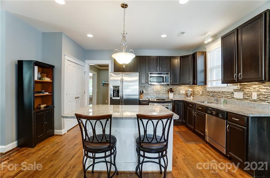 3555 Richard's Crossing Fort Mill, SC 29708 - Photo 11 of 37 a kitchen with stainless steel appliances granite countertop a stove a sink a microwave a dining table and chairs with wooden floor