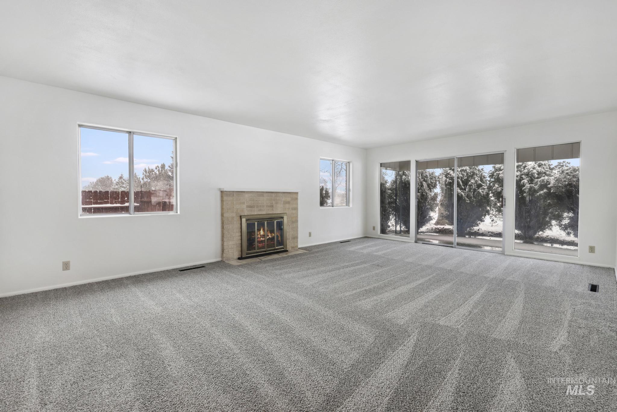 409 Clear Lakes Road Buhl, ID 83316 - Photo 5 of 43 Unfurnished living room with plenty of natural light, carpet flooring, and a tiled fireplace