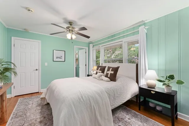 a bedroom with a bed potted plant on the dresser and a large window
