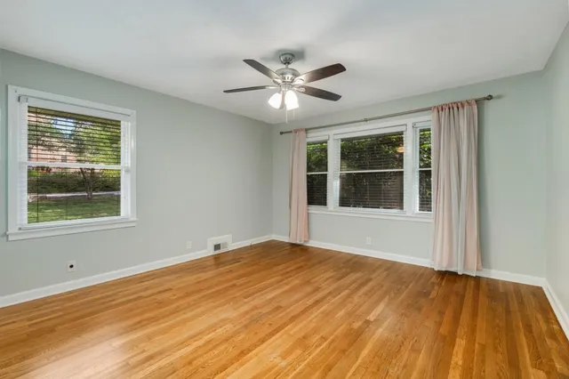a view of an empty room with window and wooden floor