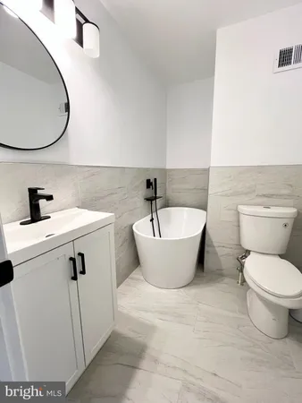 a white toilet sitting next to a white sink and vanity