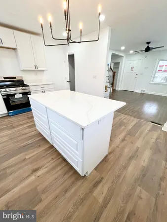 a large kitchen with stainless steel appliances wooden floor and a refrigerator