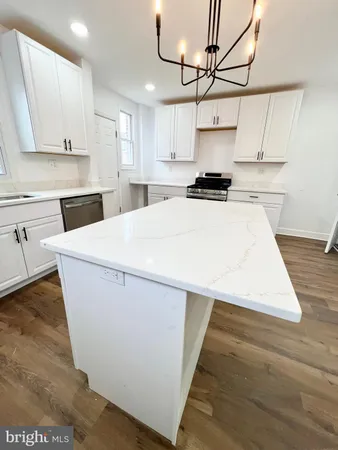 a kitchen with stainless steel appliances granite countertop a refrigerator a stove and white cabinets with wooden floor
