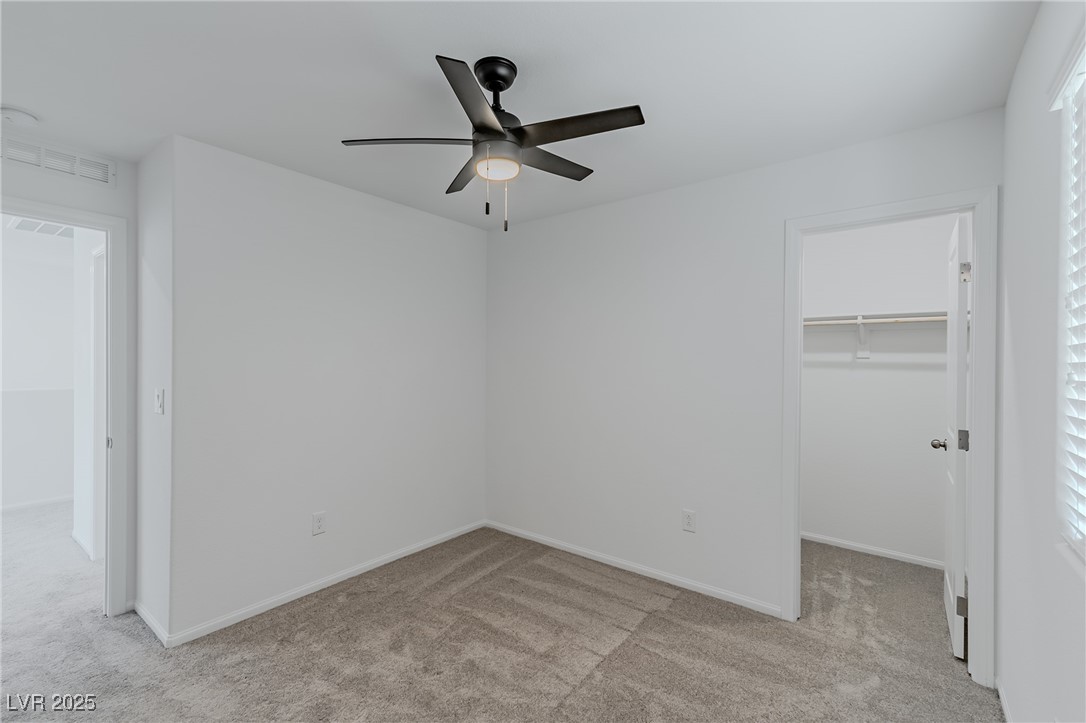 7859 Lacemaker Court Las Vegas, NV 89113 - Photo 16 of 24 Unfurnished bedroom with a walk in closet, light colored carpet, and a ceiling fan