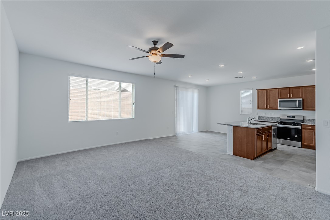 7859 Lacemaker Court Las Vegas, NV 89113 - Photo 24 of 24 Kitchen featuring open floor plan, appliances with stainless steel finishes, light colored carpet, a center island with sink, and brown cabinets