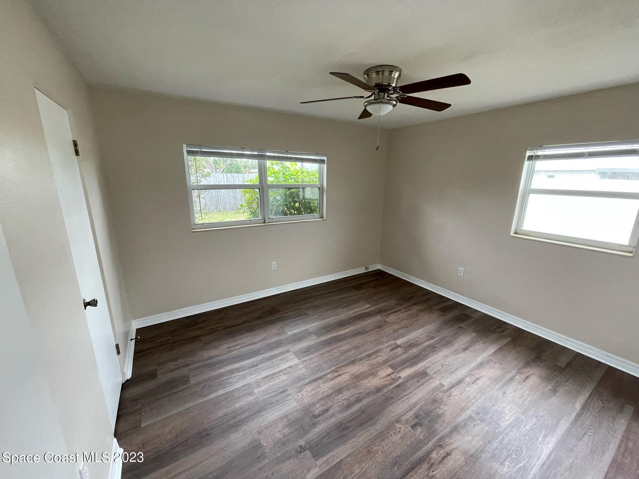 1820 Harrison Avenue Melbourne, FL 32935 - Photo 11 of 20 an empty room with wooden floor fan and windows