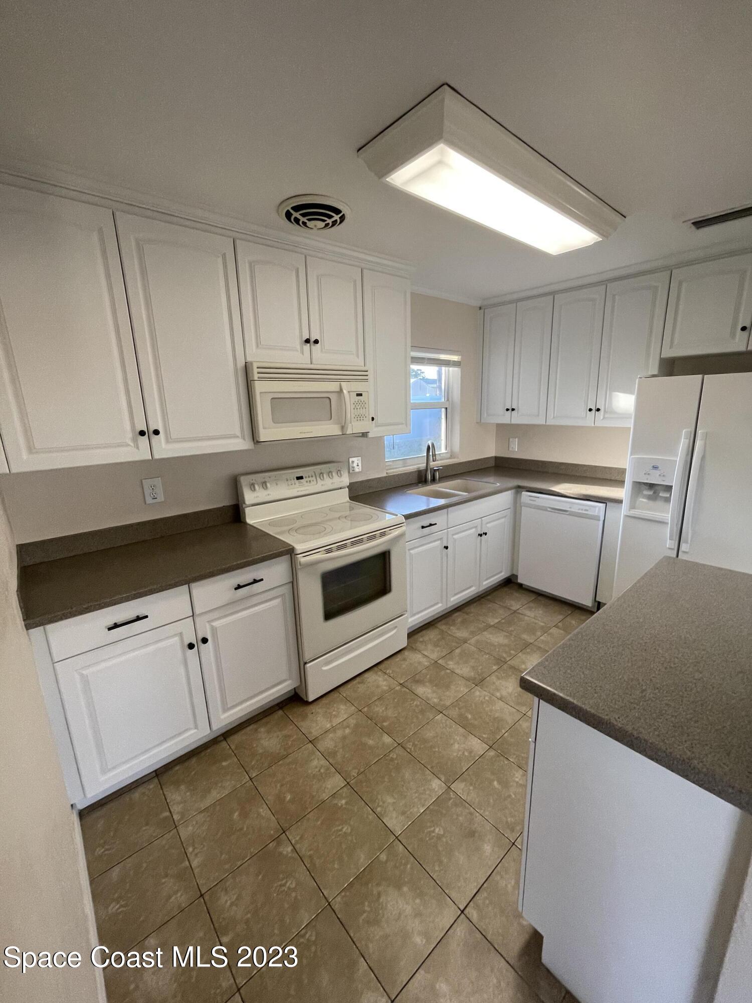 1820 Harrison Avenue Melbourne, FL 32935 - Photo 7 of 20 a kitchen with a cabinets and white appliances