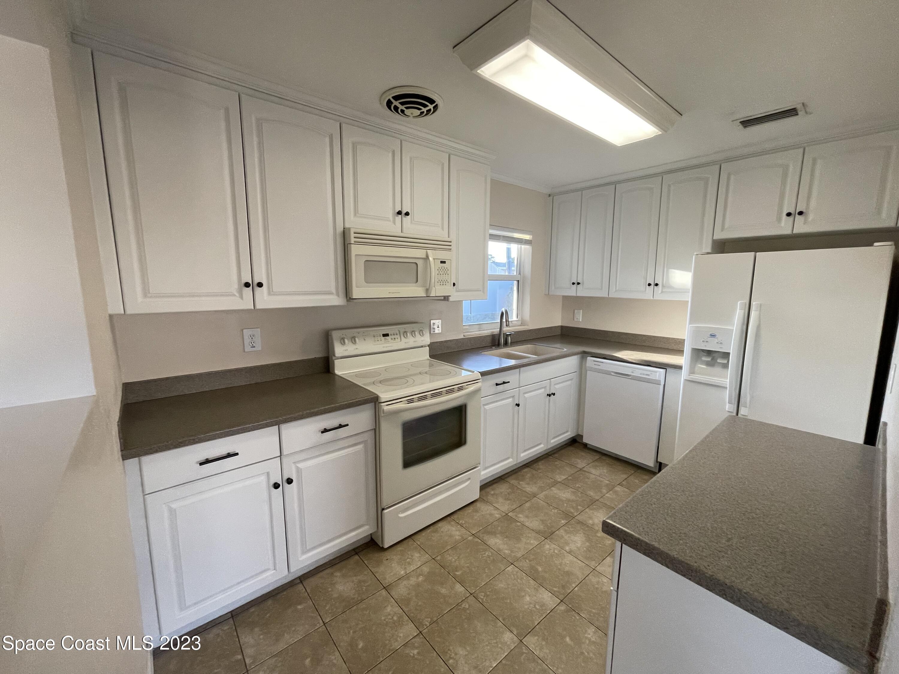 1820 Harrison Avenue Melbourne, FL 32935 - Photo 8 of 20 a kitchen with white cabinets stainless steel appliances and sink