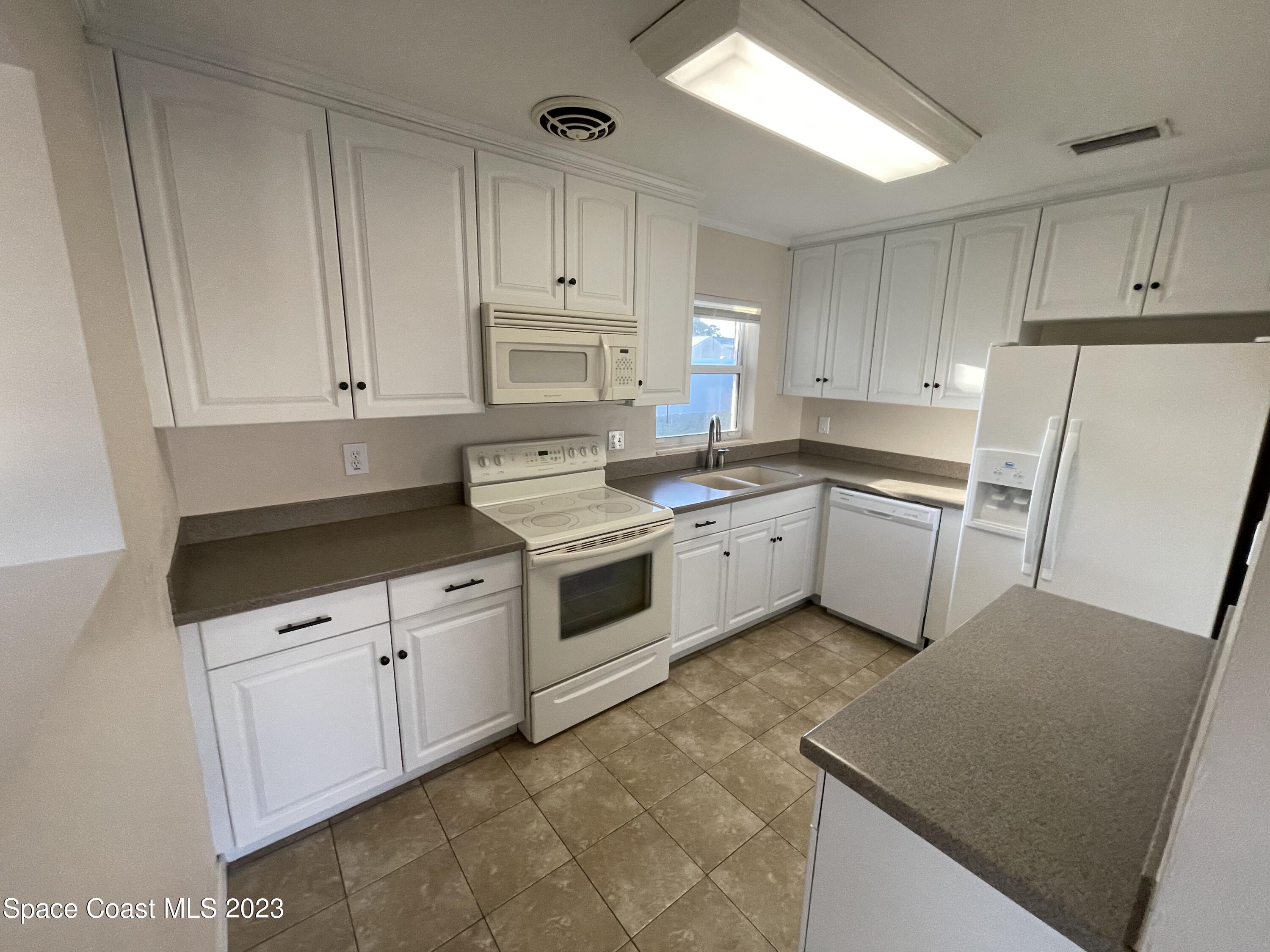 1820 Harrison Avenue Melbourne, FL 32935 - Photo 9 of 20 a kitchen with white cabinets and white appliances