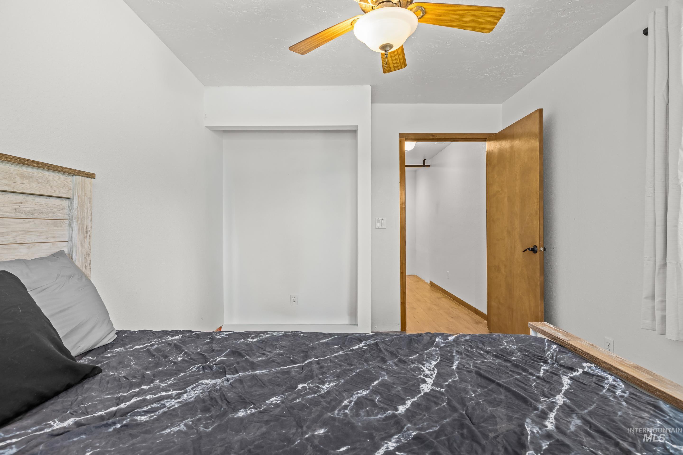 92 Cruickshank Road Horseshoe Bend, ID 83629 - Photo 28 of 50 Bedroom featuring a light wood-finish headboard, a ceiling fan with light fixture, and a doorway leading to an interior space with wood-finish flooring