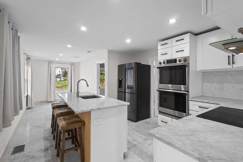 7 Darrow Street Worcester, MA 01606 - Photo 13 of 42 a kitchen with stainless steel appliances kitchen island granite countertop a refrigerator and a stove top oven with white countertops