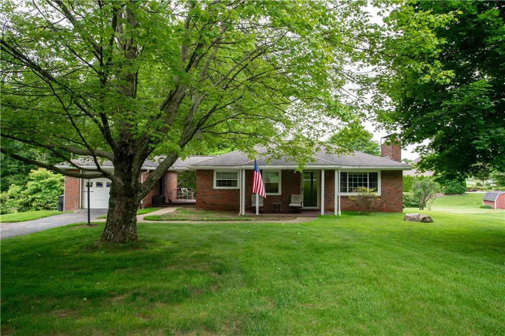 a view of a house with a big yard and large trees