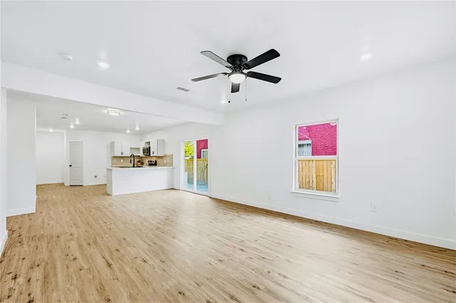 a kitchen with granite countertop a stove a sink dishwasher and white cabinets with wooden floor