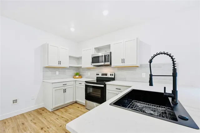 a kitchen with stainless steel appliances granite countertop a sink stove and cabinets