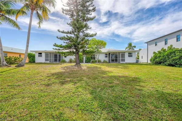 a view of a house with a big yard and palm trees