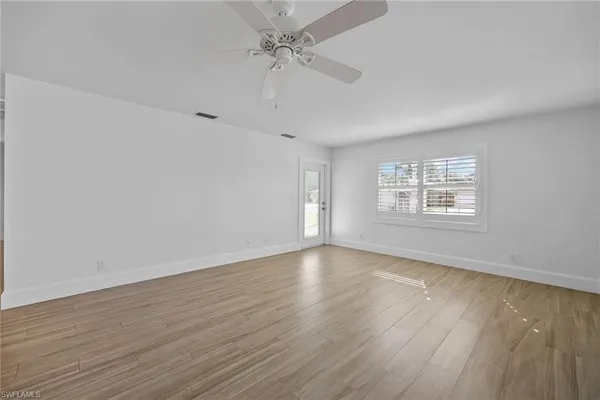 a view of an empty room with wooden floor and a window