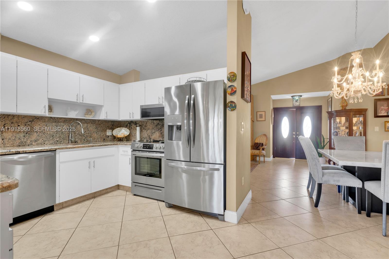 11365 Southwest 143rd Court Miami, FL 33186 - Photo 18 of 40 a kitchen with granite countertop a refrigerator a stove top oven and cabinets