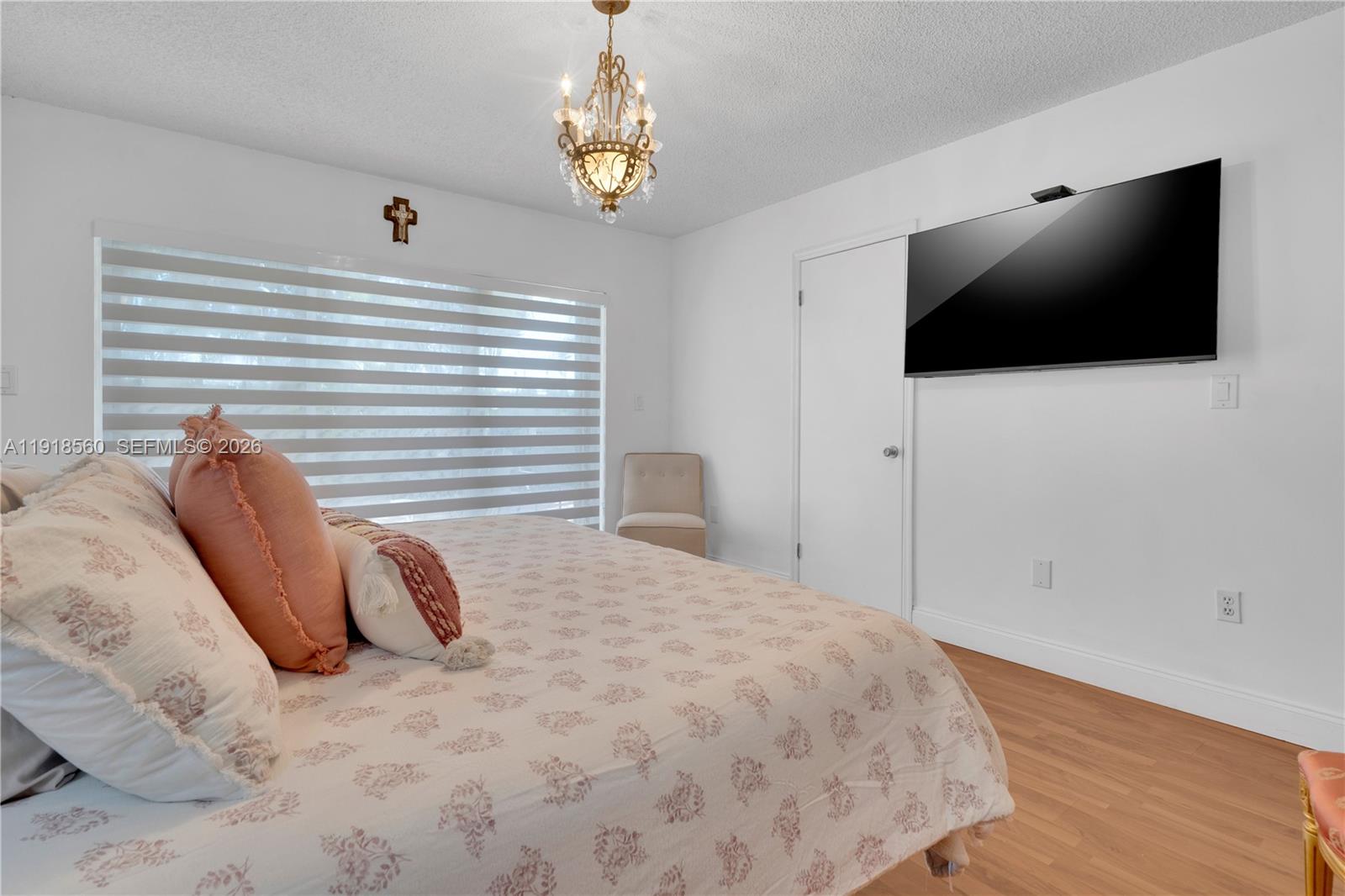 11365 Southwest 143rd Court Miami, FL 33186 - Photo 31 of 40 a bedroom with a bed a flat screen tv and a chandelier