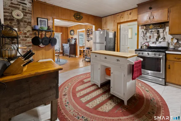 a room with stainless steel appliances kitchen island granite countertop a stove and white cabinets