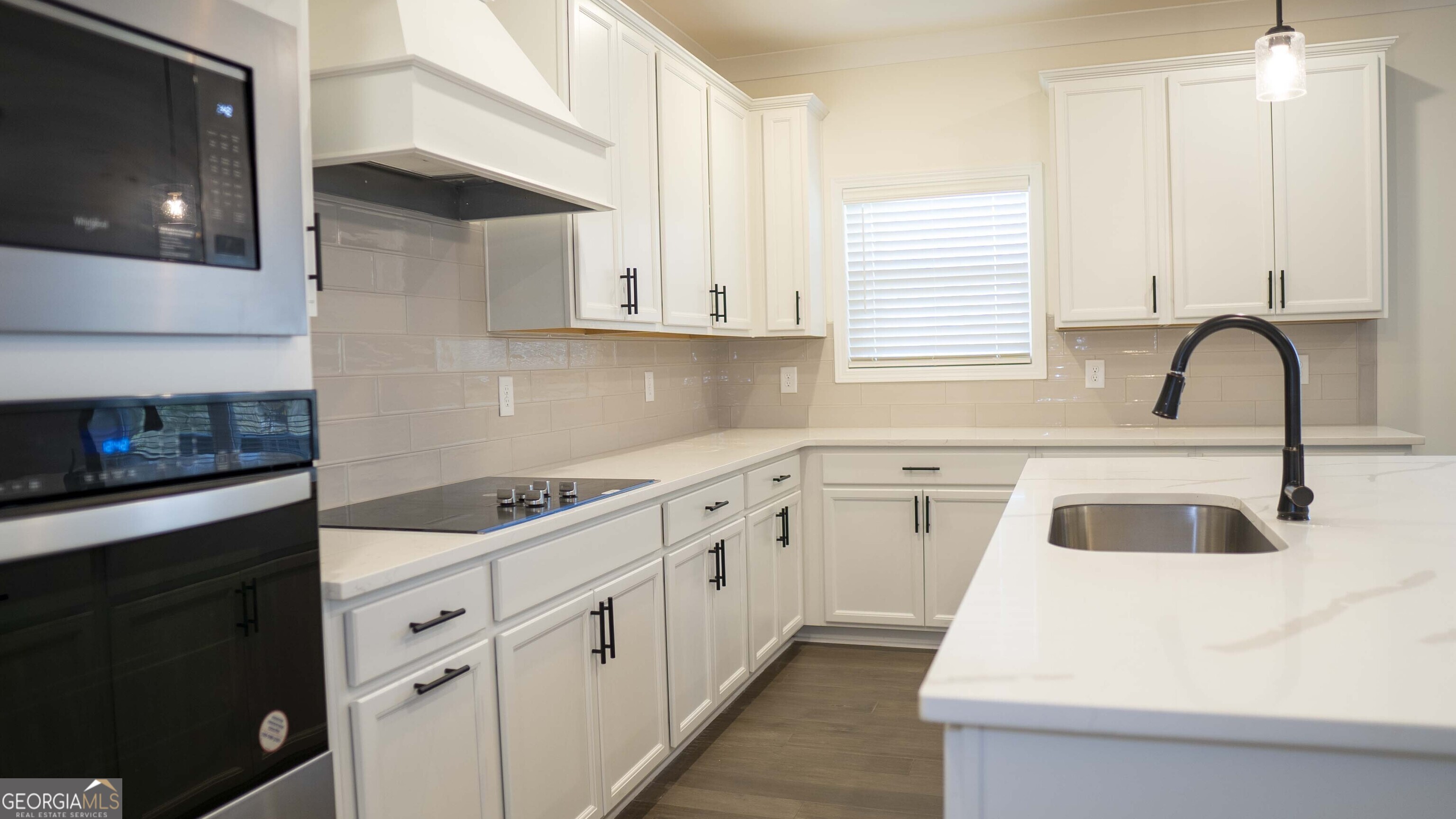 604 Beaver Court Perry, GA 31069 - Photo 14 of 40 a kitchen with white cabinets a sink and a stove with wooden floor