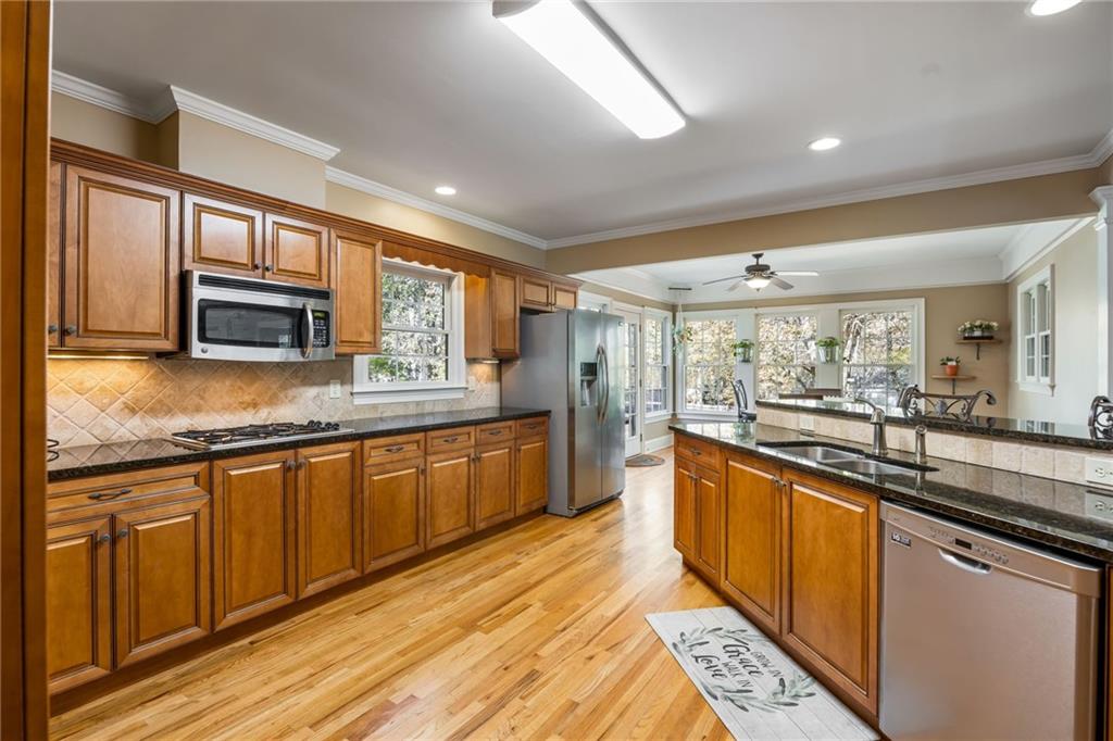 1505 Old John Ward Road Marietta, GA 30064 - Photo 13 of 50 a large kitchen with stainless steel appliances granite countertop a large stove top oven a sink dishwasher a dining table and chairs with wooden cabinets