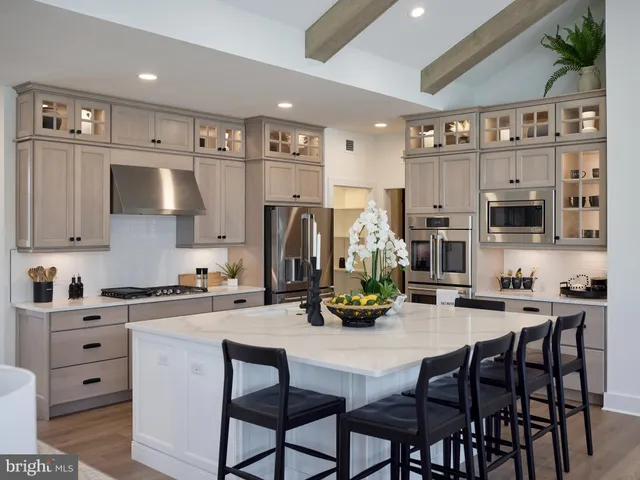 a kitchen with stainless steel appliances a sink a stove a table and chairs