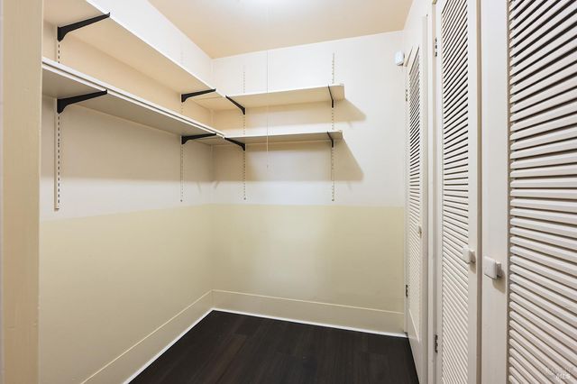 a view of an empty room with wooden floor fireplace and a window
