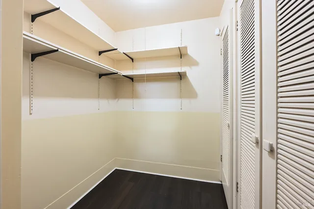 a view of an empty room with wooden floor fireplace and a window