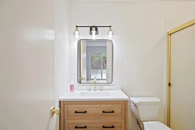 a bathroom with a toilet sink vanity and mirror