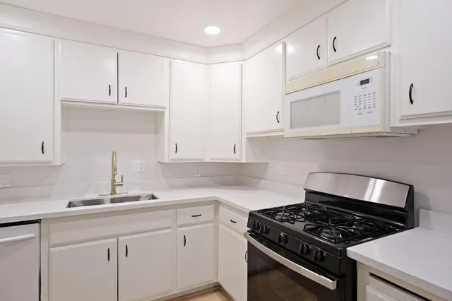 a kitchen with granite countertop white cabinets and stainless steel appliances